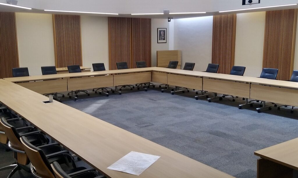 Empty council meeting room with desks arranged in a U shape